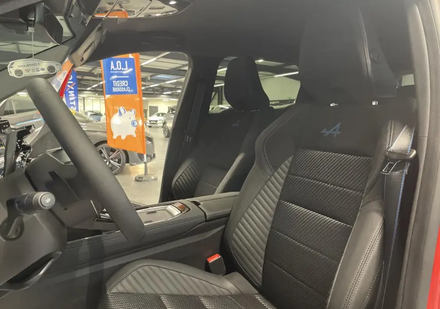 Vue intérieure côté conducteur du Renault Austral 2025, sièges en tissu carbone Alcantara noir avec surpiqûres tricolores et logo Alpine.