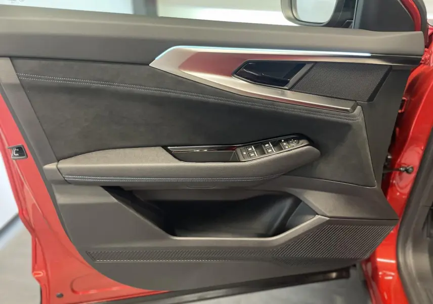 Porte avant gauche rouge métallisé de Renault Austral 2025 avec garniture Alcantara noire et commandes de vitres.