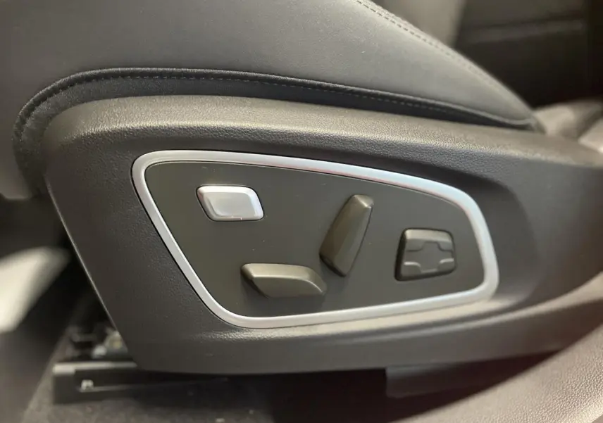 Gros plan sur les commandes électriques de réglage du siège conducteur du Renault Austral rouge métallisé.