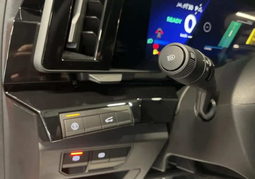 Détail intérieur du tableau de bord noir brillant du Renault Austral 2025 avec commandes éclairées et écran numérique.