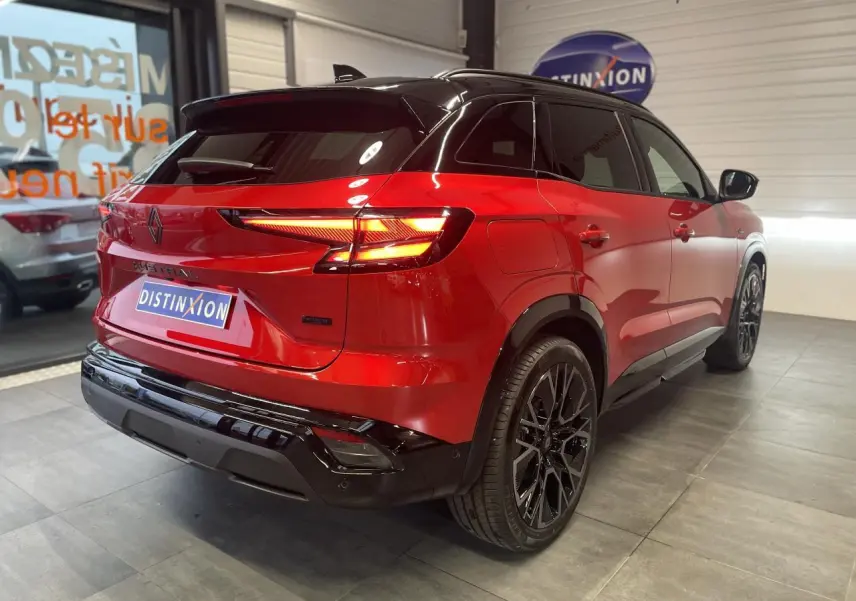 Vue 3/4 arrière droite du Renault Austral rouge métallisé avec toit noir et jantes alliage noires.