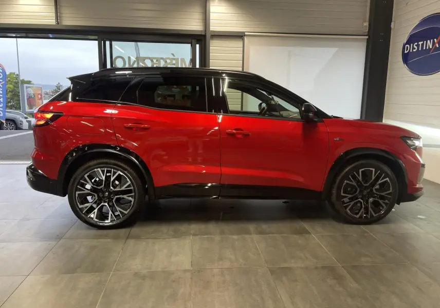 Renault Austral 1.2 E-Tech Hybride rouge métallisé avec toit noir, vue de profil côté gauche en intérieur showroom.