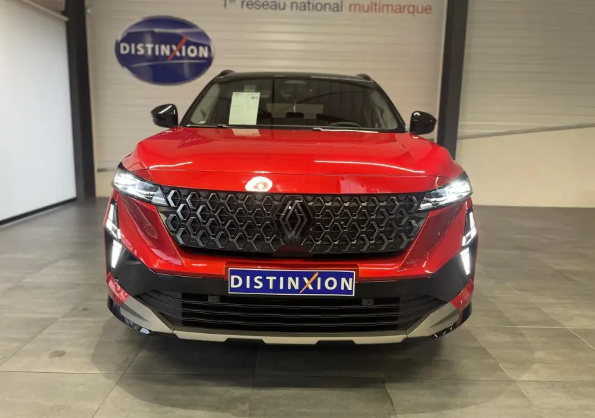 Vue frontale du Renault Austral rouge métallisé avec calandre noire et toit noir en showroom.