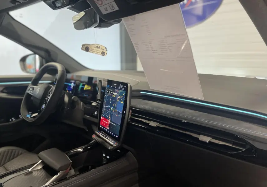 Intérieur Renault Austral 2025 vu côté conducteur, tableau de bord noir avec écran tactile vertical et éclairage bleu.
