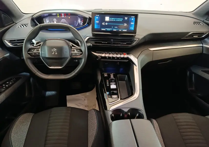 Vue intérieure avant du Peugeot 5008 2023, tableau de bord noir avec écran tactile central et volant cuir multifonctions.