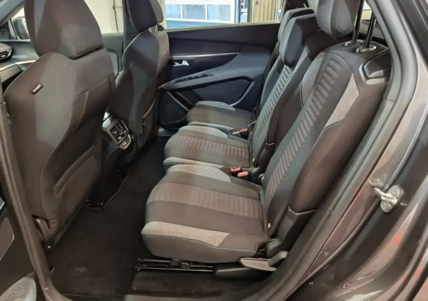 Vue côté droit sur les sièges arrière gris foncé et tissu du Peugeot 5008 2023, avec porte ouverte et habillage intérieur.