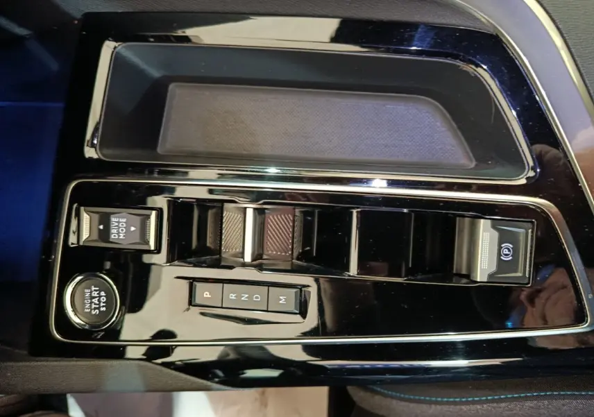 Gros plan sur la console centrale noire brillante du Peugeot 5008 2023 avec boutons de boîte auto et démarrage moteur.