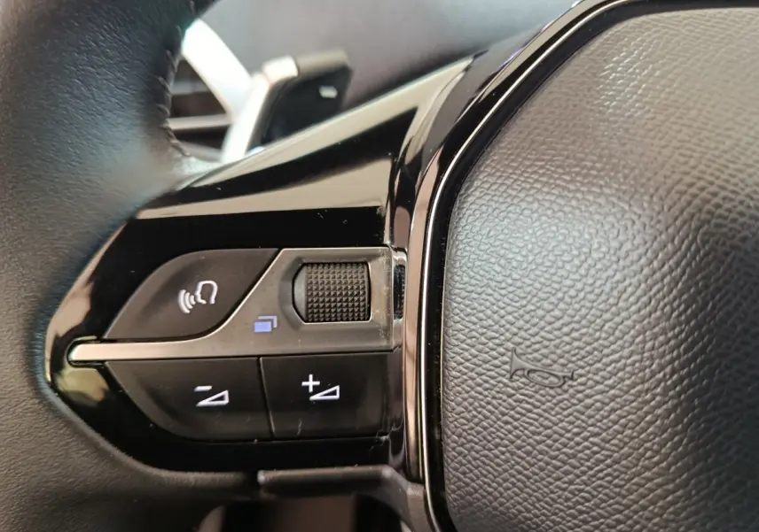 Gros plan sur les commandes multifonctions du volant cuir noir du Peugeot 5008 gris clair, version 2023.