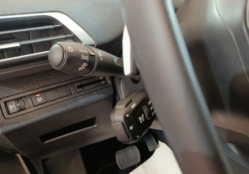 Gros plan sur la partie gauche du tableau de bord et volant cuir du Peugeot 5008 gris clair 2023.