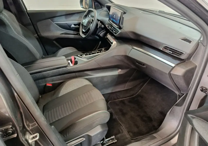 Vue intérieure côté passager du Peugeot 5008 gris clair 2023, mettant en valeur le tableau de bord et les sièges tissu noirs.