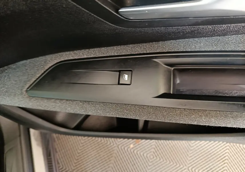 Détail du bouton de commande de vitre électrique sur la porte intérieure côté conducteur du Peugeot 5008 gris clair 2023.