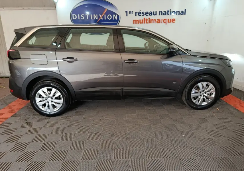 Profil droit d'un Peugeot 5008 gris clair 2023, SUV familial avec jantes alliage et lignes épurées.