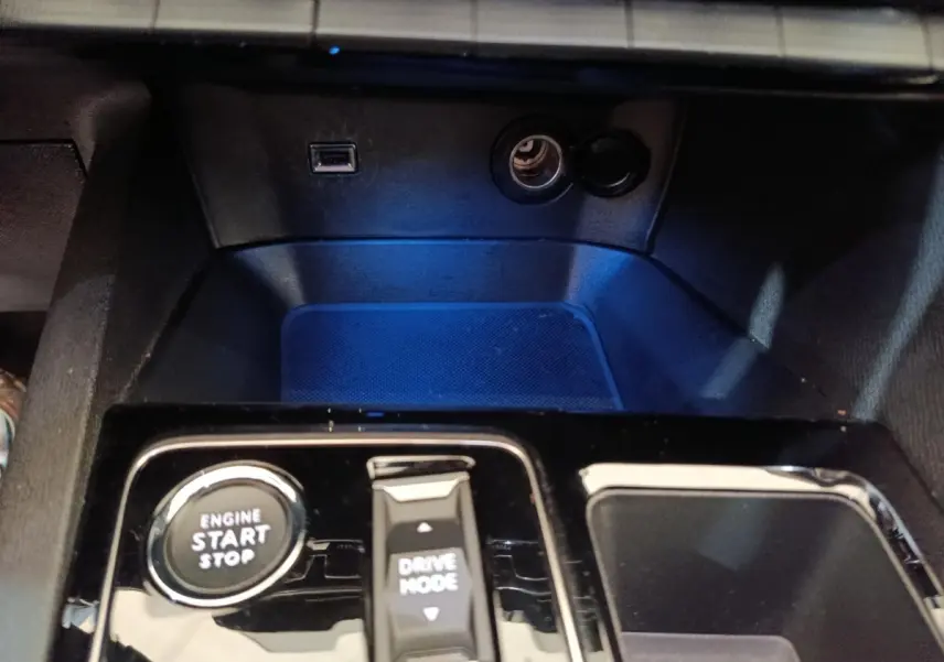 Gros plan sur la console centrale noire brillante du Peugeot 5008 gris clair, avec bouton démarrage et commande Drive Mode.