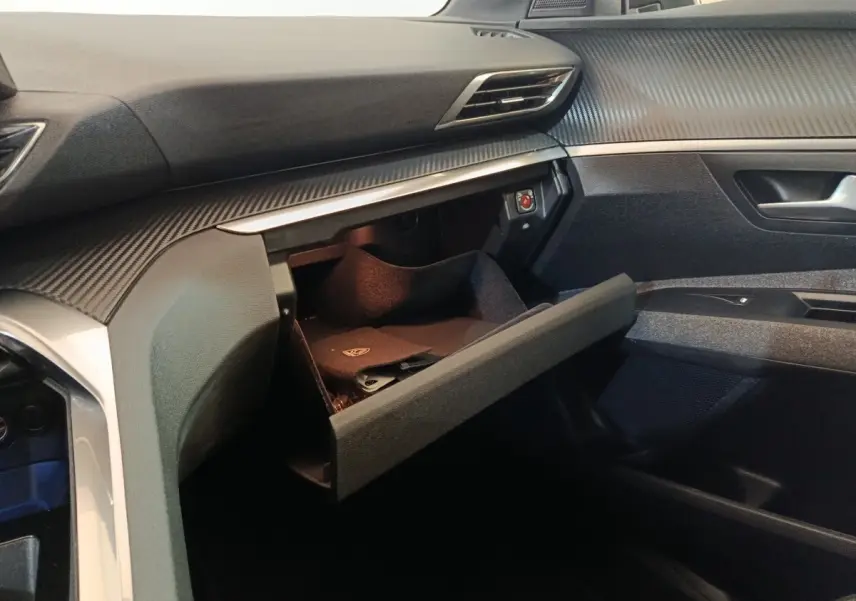 Intérieur côté passager du Peugeot 5008 gris clair 2023, avec boîte à gants ouverte et tableau de bord moderne.