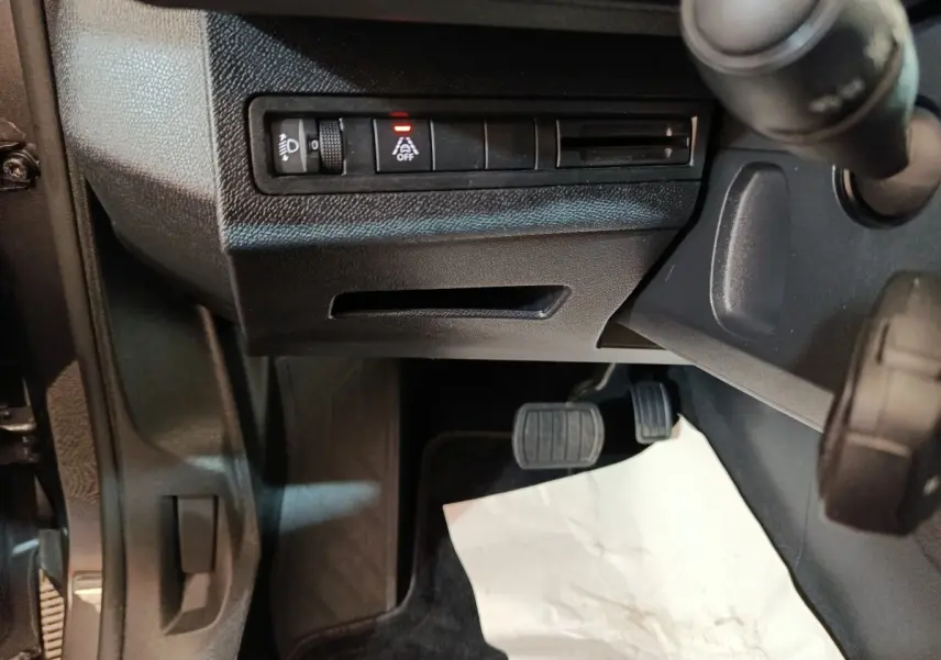 Vue intérieure côté conducteur du Peugeot 5008 2023, montrant les pédales et commandes sous le tableau de bord noir.