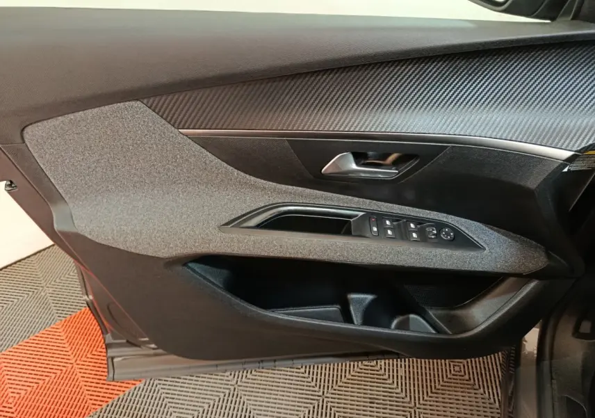 Vue rapprochée de la porte avant gauche de la Peugeot 5008 gris clair, avec commandes des vitres et poignée intégrée.