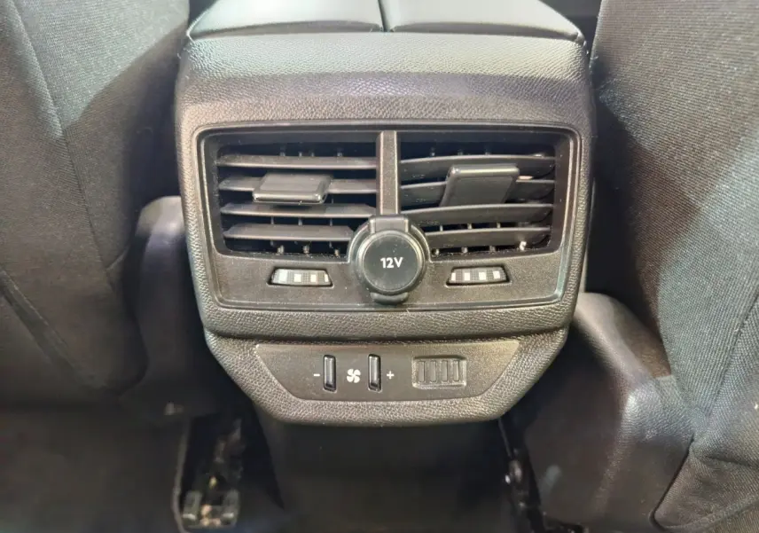 Vue rapprochée des aérateurs arrière et prise 12V noirs du Peugeot 5008 gris clair, avec commandes de ventilation.