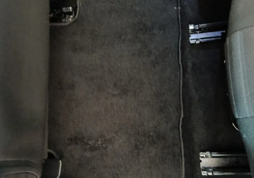 Vue rapprochée du sol entre les sièges arrière d’un Peugeot 5008 gris clair, avec tapis de sol noir.