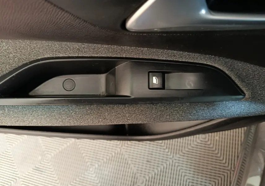 Détail de la commande de lève-vitre électrique sur la porte intérieure côté gauche du Peugeot 5008 gris clair 2023.