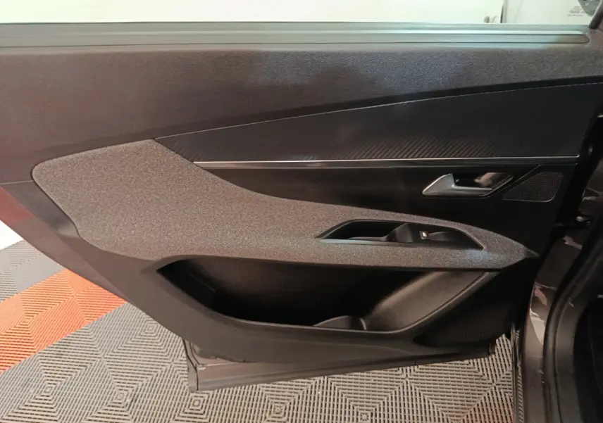 Vue rapprochée de la porte intérieure côté gauche du Peugeot 5008 gris clair, avec garniture textile et insert noir brillant.