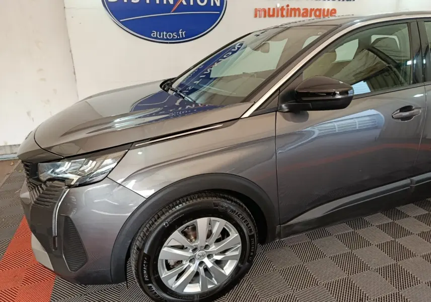 Vue 3/4 avant droit d’un Peugeot 5008 gris clair 2023 avec jantes alliage et rétroviseur noir brillant.