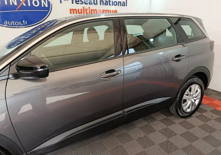 Profil droit du Peugeot 5008 gris clair 2023, mettant en valeur ses lignes épurées et ses rétroviseurs noirs brillants.