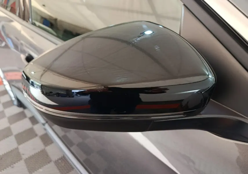 Rétroviseur noir brillant côté gauche d’un Peugeot 5008 gris clair, vue rapprochée sur la portière.