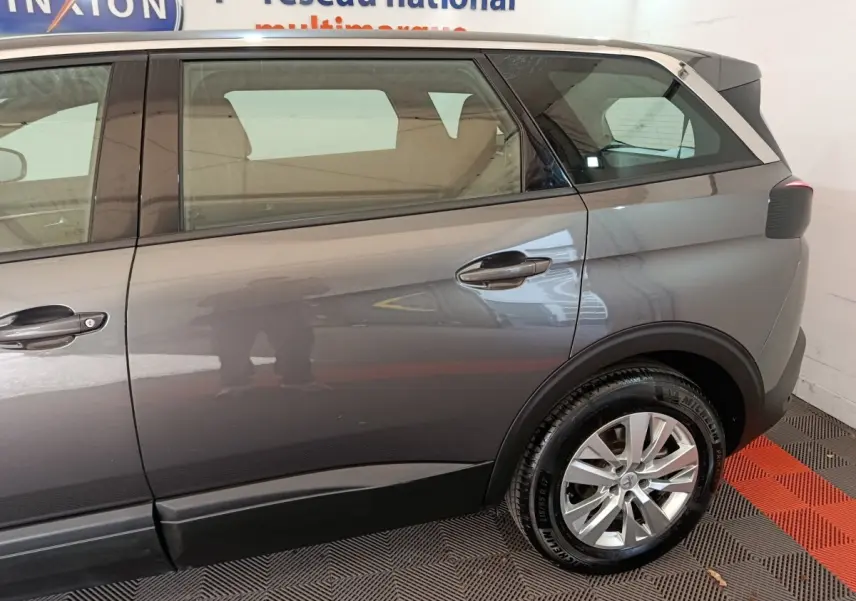 Vue latérale côté droit du Peugeot 5008 gris clair, mettant en valeur la porte arrière et la roue arrière.
