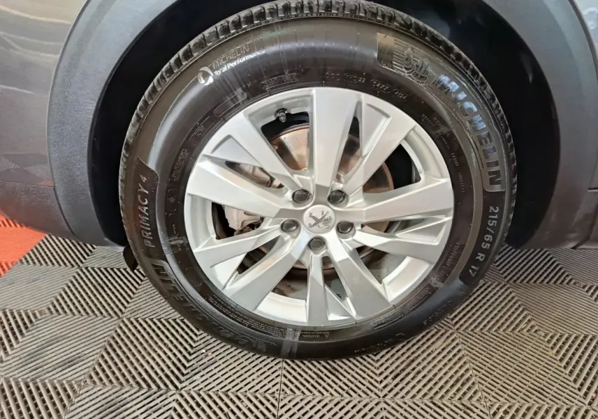 Gros plan sur la roue avant droite du Peugeot 5008 gris clair, avec jante alliage et pneu Michelin.