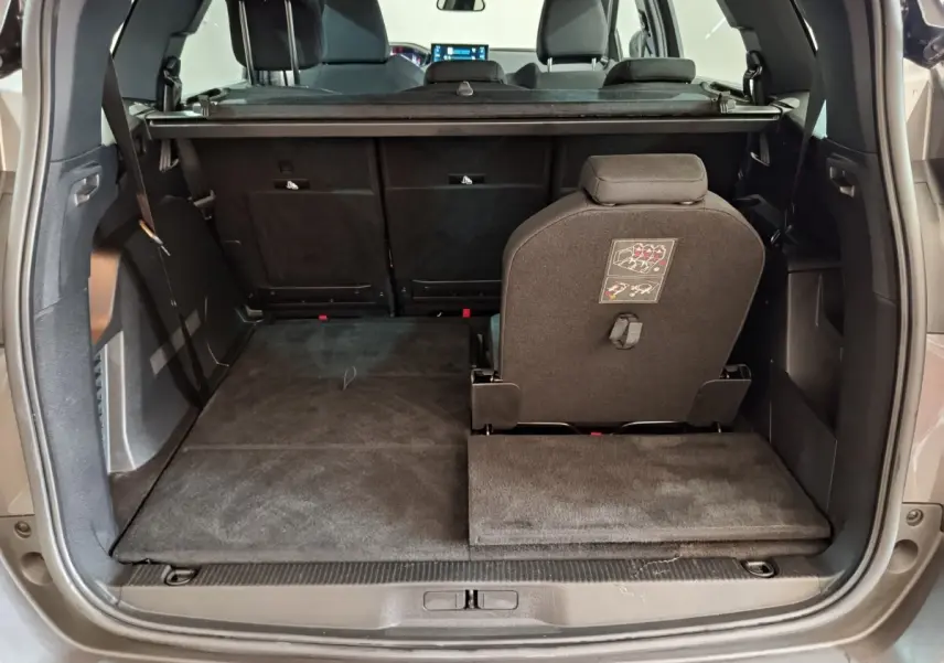 Coffre ouvert vu de l'arrière d'un Peugeot 5008 gris clair, avec siège arrière droit relevé et plancher plat.