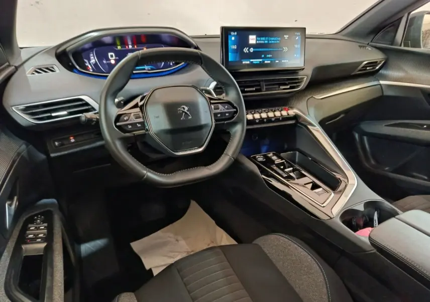 Vue intérieure côté conducteur du Peugeot 5008 2023, volant cuir multifonctions et écran tactile central lumineux.
