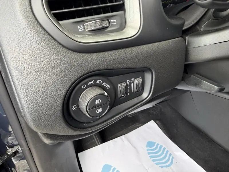 Gros plan sur le panneau de commande des phares côté gauche du tableau de bord d’un Jeep Renegade bleu métal 2024.