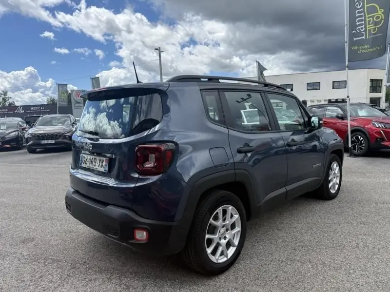 Vue 3/4 arrière droite d'un Jeep Renegade 2024 bleu métal avec jantes argentées et toit noir en concession.
