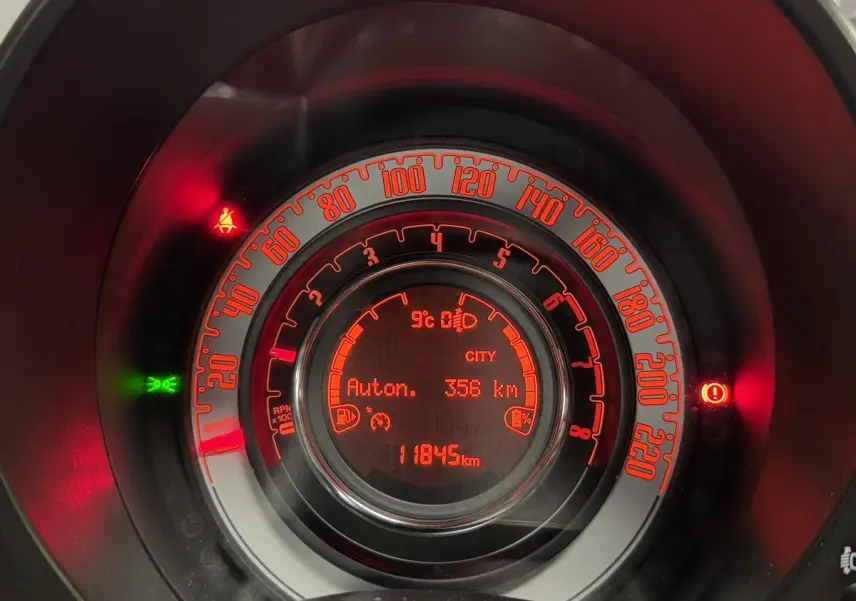 Gros plan sur le combiné d'instrumentation rouge de la Fiat 500 Cabriolet noire affichant 11845 km et autonomie 356 km.