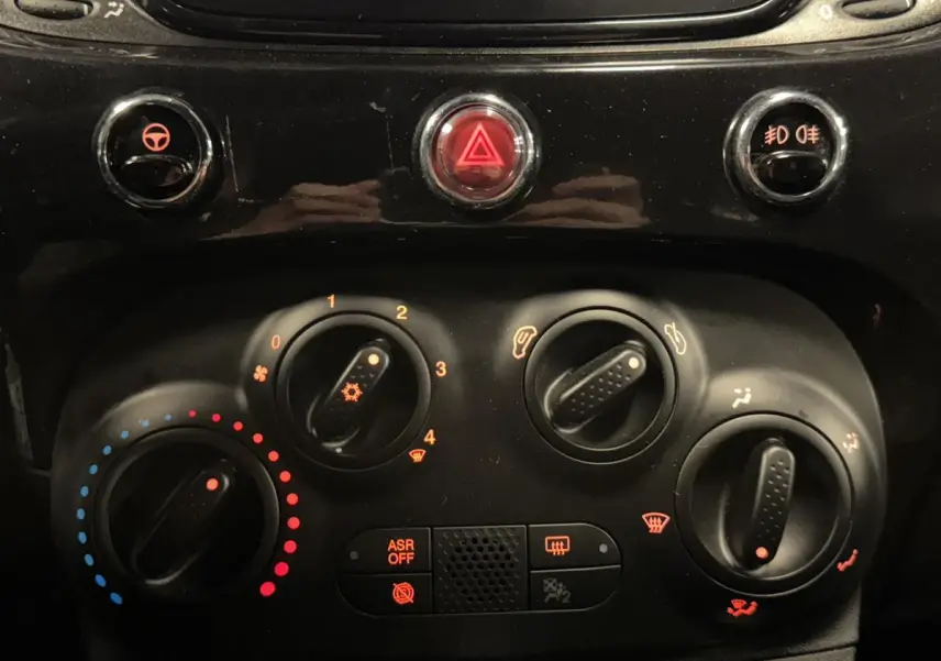 Gros plan sur la console centrale noire de la Fiat 500 Cabriolet 2024 avec commandes de climatisation manuelle et boutons lumineux.