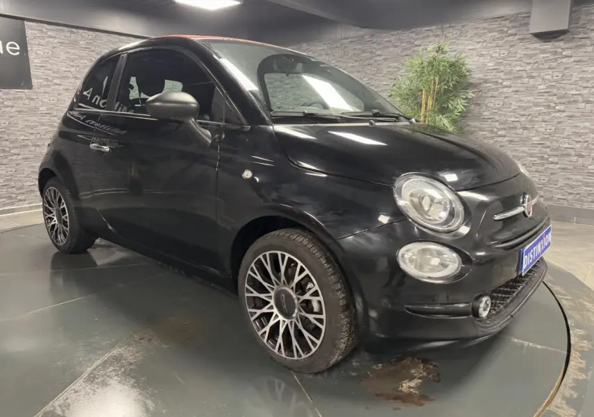 Fiat 500 noire vue 3/4 avant droit, avec jantes alliage et calandre distinctive dans un showroom.