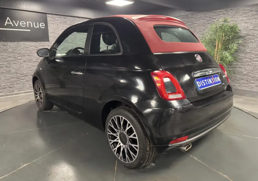 Fiat 500 Cabriolet 2024 vue 3/4 arrière côté droit, noire métallisée avec capote rouge et jantes alliage 16 pouces.