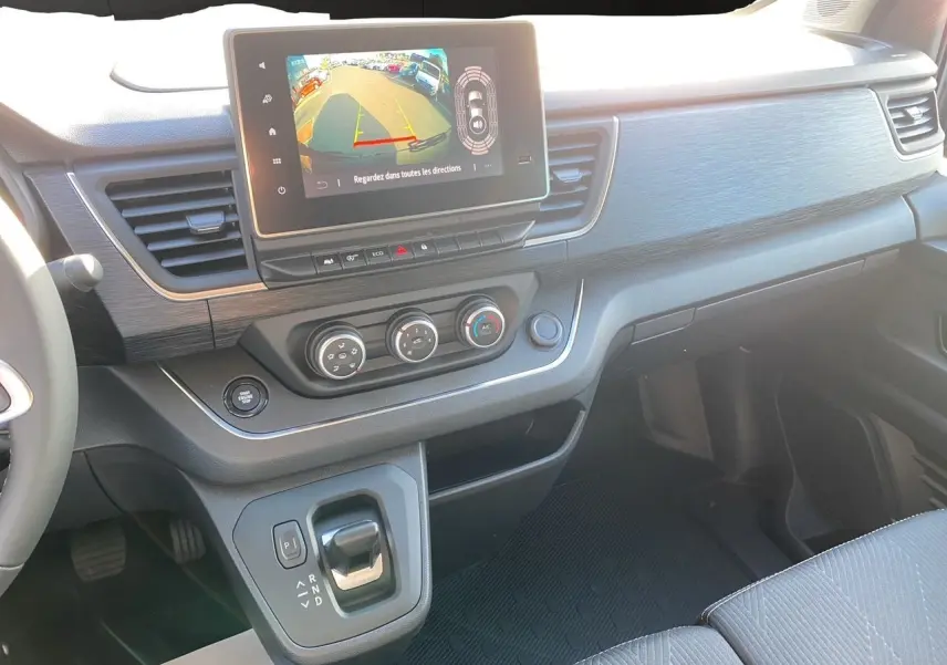 Intérieur avant du Renault Trafic Combi noir 2025, tableau de bord avec écran tactile et levier de boîte automatique.