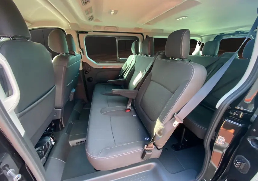 Vue intérieure côté gauche du Renault Trafic Combi noir 2025 montrant les sièges tissu noir et la porte coulissante ouverte.