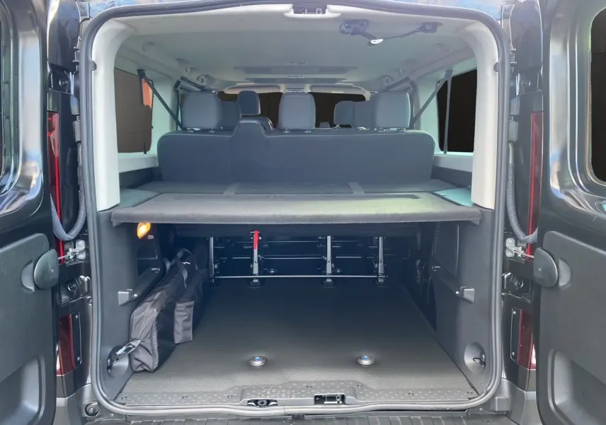 Vue arrière du Renault Trafic Combi noir 2025, coffre ouvert montrant banquette arrière et espace de chargement organisé.