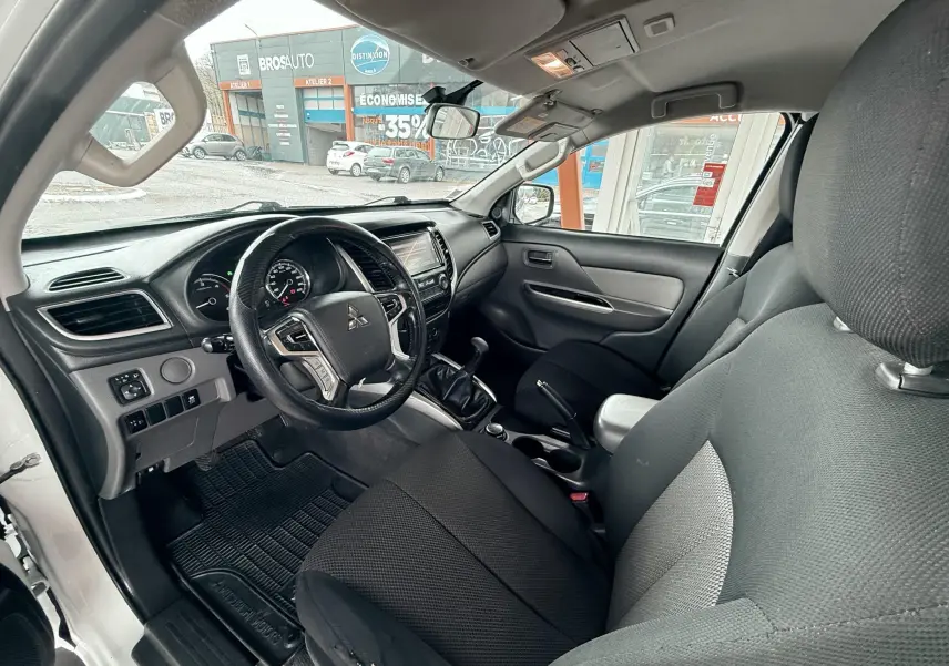 Intérieur noir du Mitsubishi L200 Club Cab 2017, vue côté conducteur montrant le tableau de bord et volant cuir.