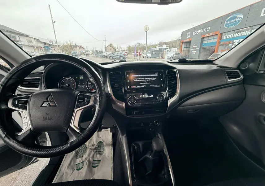 Vue intérieure avant du Mitsubishi L200 Club Cab 2017, tableau de bord noir avec volant multifonction et écran central tactile.