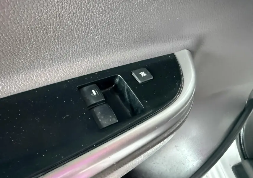 Gros plan sur les commandes de lève-vitre et verrouillage sur la porte intérieure noire du Mitsubishi L200 blanc.