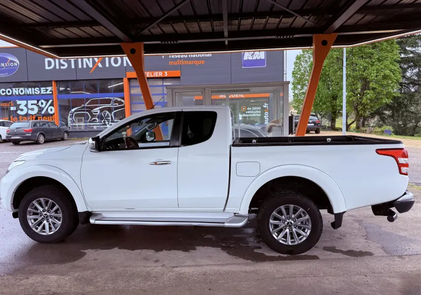 Vue de profil côté gauche du pick-up Mitsubishi L200 Club Cab blanc, avec benne ouverte et jantes alliage visibles.