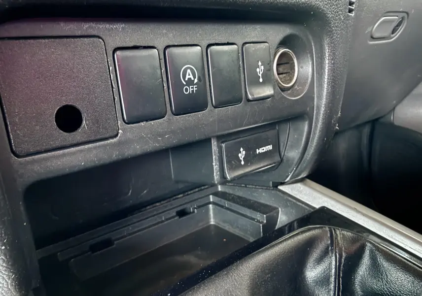 Gros plan sur la console centrale noire du Mitsubishi L200 Club Cab 2017, montrant les boutons de commande et prise USB/HDMI.