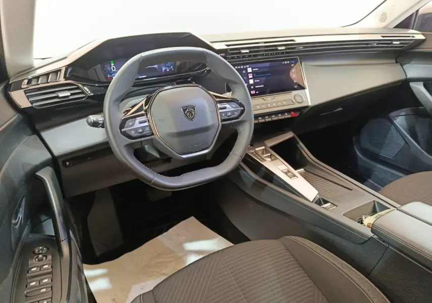 Vue intérieure du poste de conduite de la Peugeot 308 2022, volant cuir multifonctions et écran tactile central.