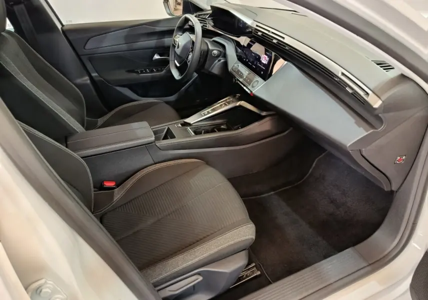Intérieur avant droit de la Peugeot 308 blanche 2022, avec tableau de bord digital et sièges tissu noirs.