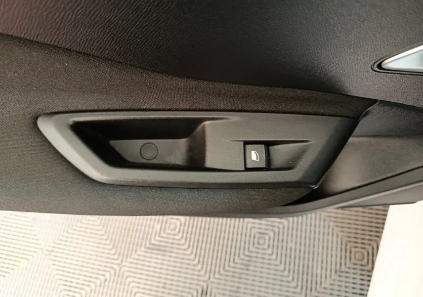 Gros plan sur la commande de lève-vitre côté droit intérieur de la Peugeot 308 blanche, version 2022.