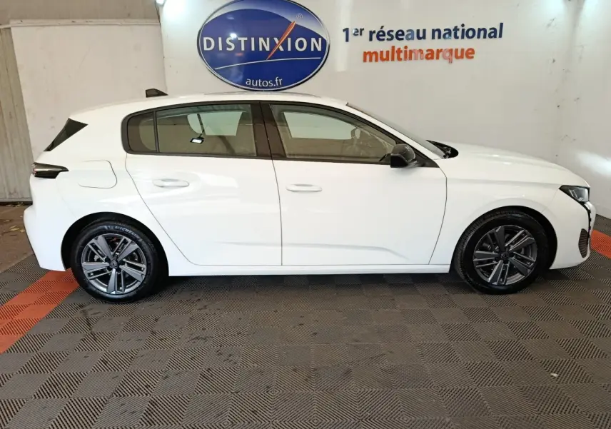 Peugeot 308 blanche vue de profil côté gauche, avec jantes alliage et rétroviseurs noirs contrastants.