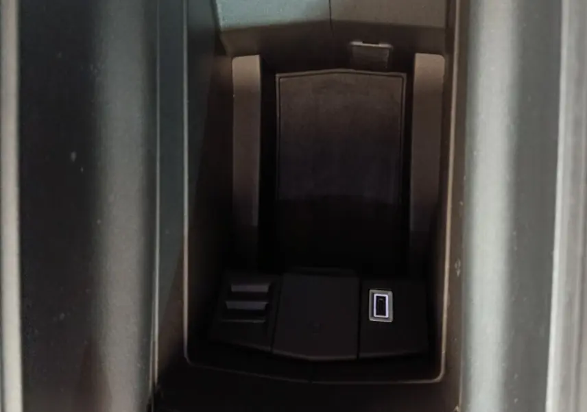 Vue rapprochée de la console centrale noire de la Peugeot 308 blanche, avec port USB visible dans l'accoudoir.